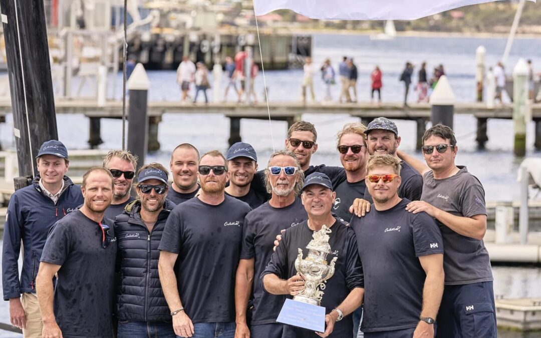 Sam Haynes holds Tattersall Cup trophy surrounded by his smiling crew after Sydney to Hobart Yacht Race