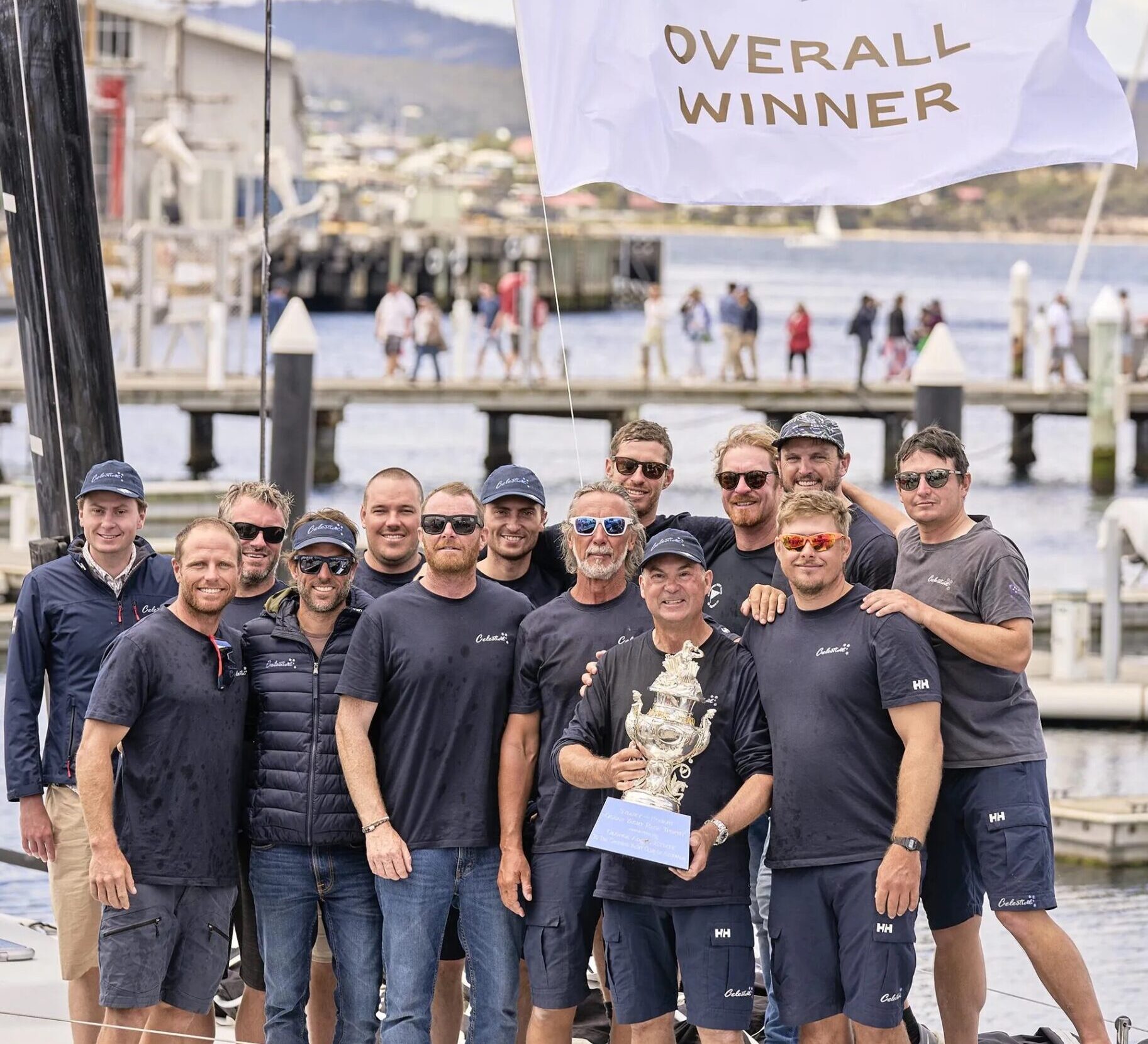 Sam Haynes holds Tattersall Cup trophy surrounded by his smiling crew after Sydney to Hobart Yacht Race